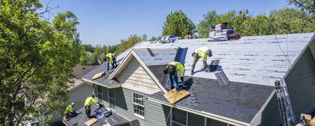 Team of roofers working on a roof with visible roof underlayment, prompting the question: what is roof underlayment?