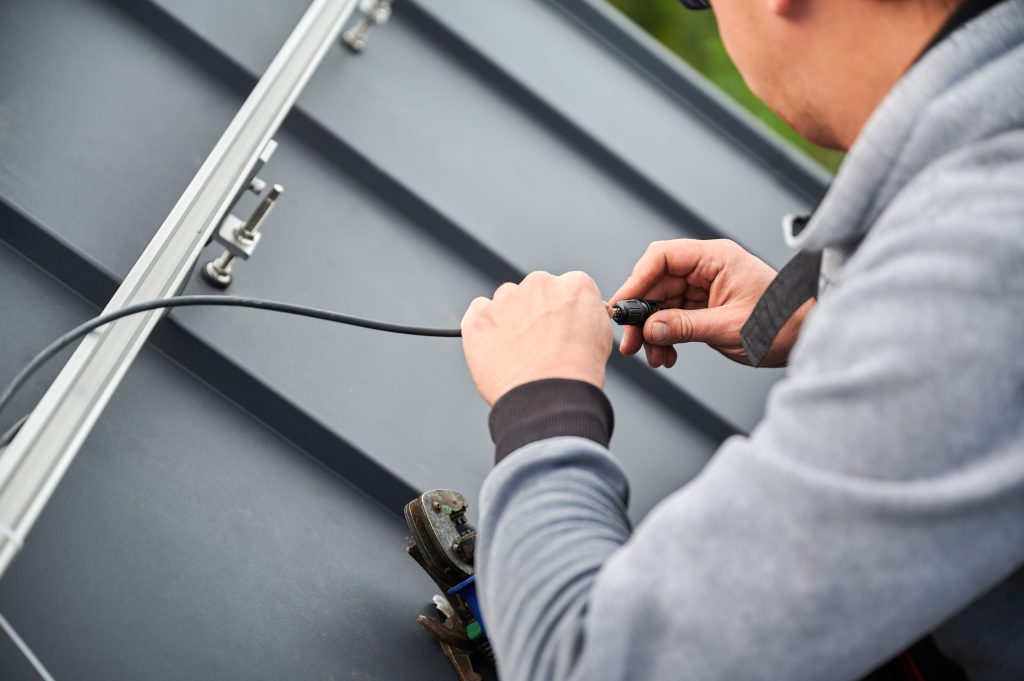 Person installing roof heat cables on a home, addressing the question are roof heat cables dangerous for preventing ice dams in winter.