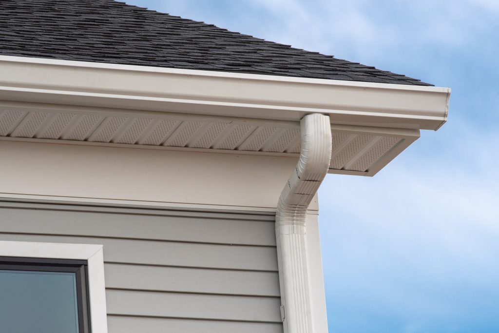 gutter installation on a roof and house corner with visible soffits, answering the question "What are soffits?"